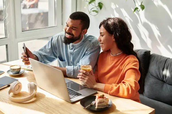 Una pareja afroamericana colabora en proyectos independientes mientras saborea deliciosas golosinas. - foto de stock
