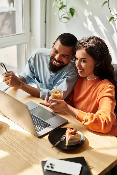 En un animado café, una feliz pareja afroamericana comparte ideas mientras trabaja remotamente. - foto de stock
