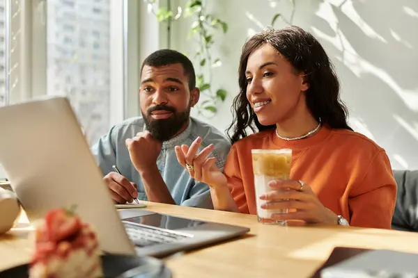 Pareja se involucra en el trabajo remoto, compartiendo ideas y bebidas en un ambiente de cafetería vibrante. - foto de stock