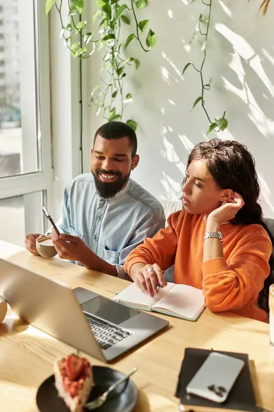 Una pareja afroamericana se dedica al trabajo freelance en un acogedor café, intercambiando ideas. - foto de stock