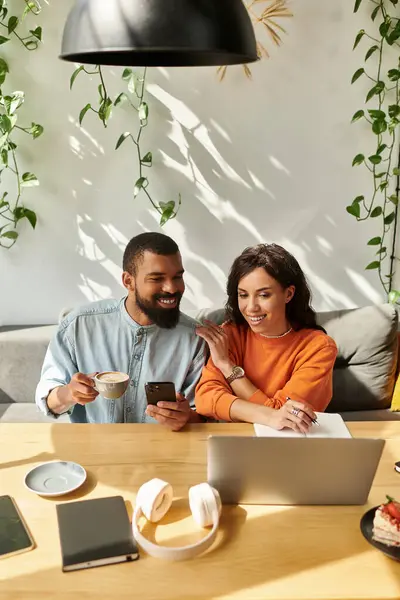 Una pareja colabora remotamente en un elegante café, inmersos en sus tareas freelance. - foto de stock
