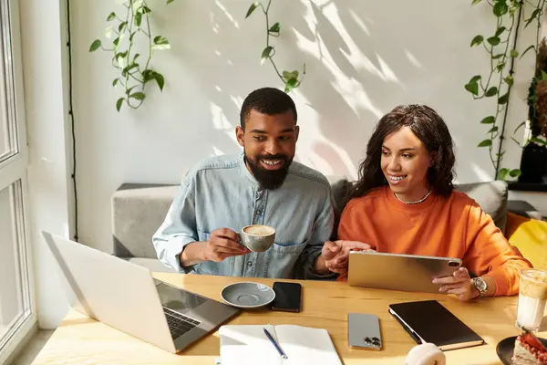In a vibrant cafe, an African American couple collaborates on freelance projects with joy. — Stock Photo