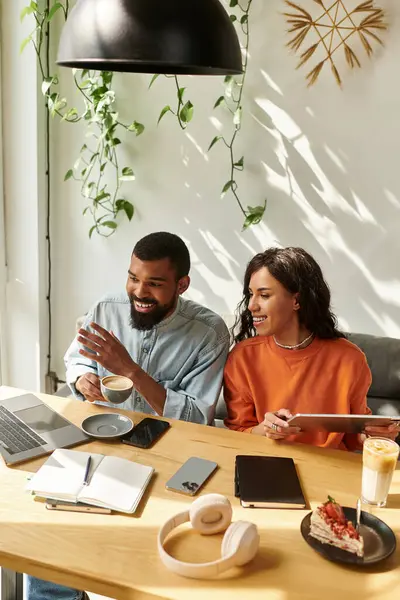 Pareja afroamericana colabora en proyectos independientes mientras toma café en un café. - foto de stock