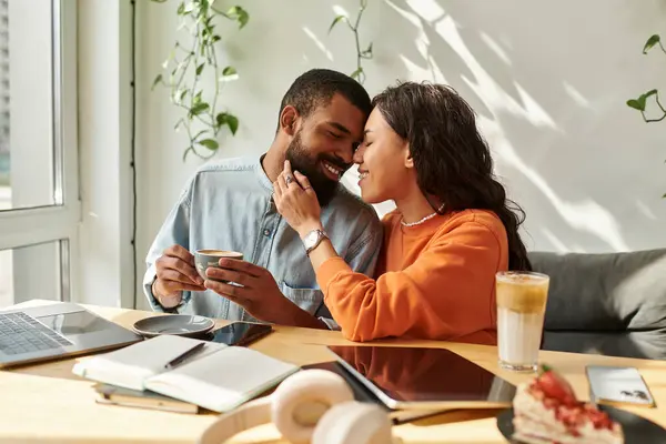 Una pareja afroamericana comparte un momento de alegría mientras trabaja remotamente en un café, tomando café. - foto de stock