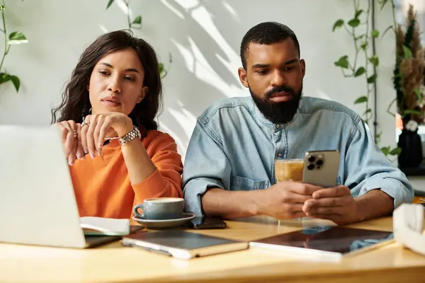 Una pareja afroamericana se centra en sus tareas mientras disfrutan de un cálido ambiente de cafetería juntos. - foto de stock