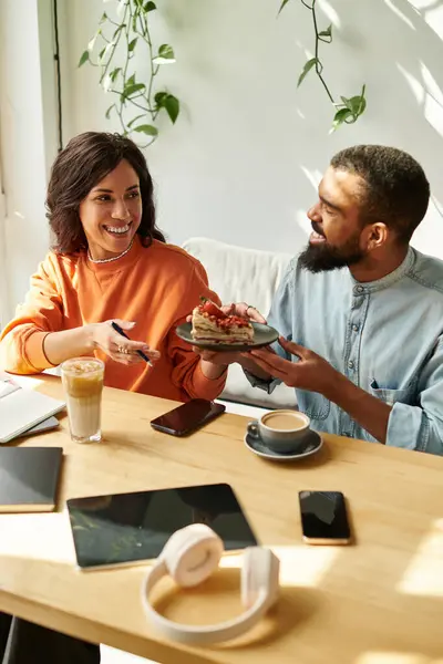 Una pareja afroamericana trabaja en proyectos independientes juntos mientras disfruta de un sabroso regalo. - foto de stock