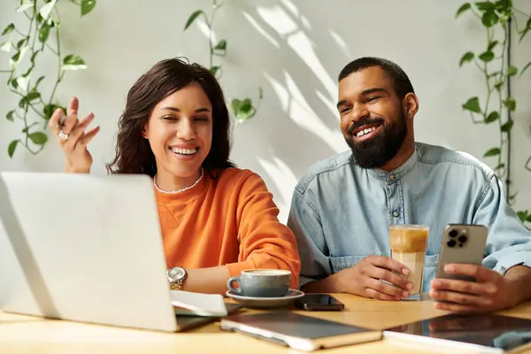 Zwei Menschen genießen die Fernarbeit in einem Café, tauschen Ideen aus und lachen bei Kaffee und Laptop. — Stockfoto