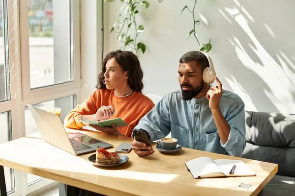 Um casal engajado em tarefas freelance, cercado por um ambiente acolhedor de café, compartilhando ideias. — Fotografia de Stock