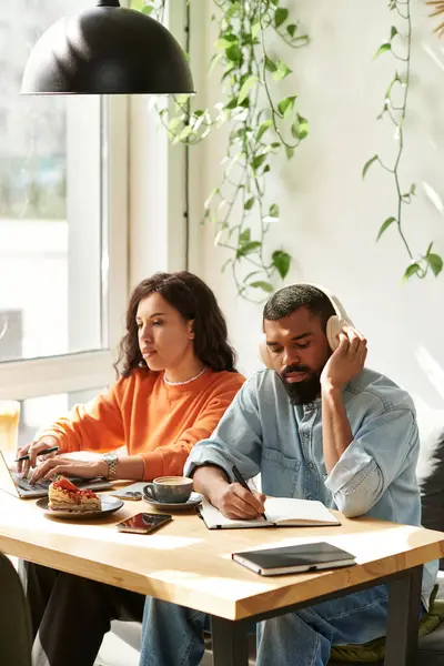 Um casal afro-americano colabora em tarefas freelance enquanto desfruta de uma atmosfera vibrante de café. — Fotografia de Stock