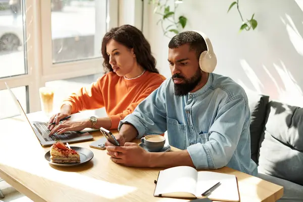 Um casal afro-americano se concentra em suas tarefas freelance em uma atmosfera vibrante de café. — Fotografia de Stock