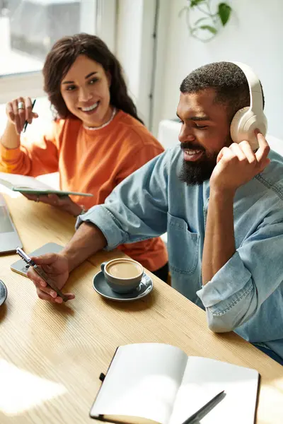 Um casal afro-americano se envolve em trabalho remoto, compartilhando ideias e criatividade em um café encantador. — Fotografia de Stock