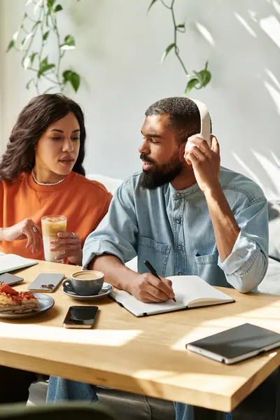 Una pareja afroamericana colabora en un café, compartiendo ideas mientras toma café. - foto de stock