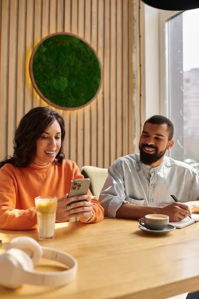Una pareja afroamericana comparte momentos alegres mientras bebe en un acogedor café mientras se conecta. - foto de stock
