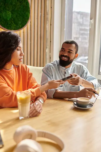 Pareja afroamericana se dedica a una cálida conversación mientras disfruta de bebidas en el café. - foto de stock