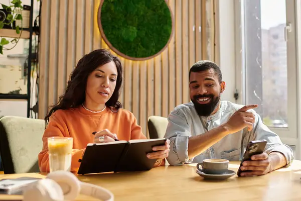 Una pareja afroamericana disfruta de bebidas y conversación en un café. - foto de stock