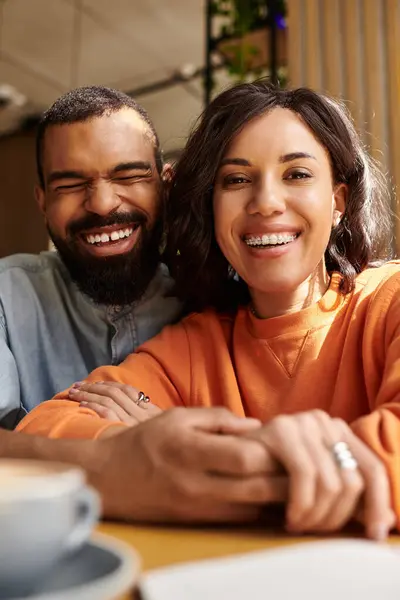 Um casal afro-americano desfruta de seu tempo juntos, trocando sorrisos e risos em um café. — Fotografia de Stock