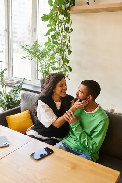 A happy couple enjoys each other's company at a bustling cafe surrounded by greenery. — Stock Photo