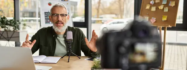 Un uomo con la barba parla appassionatamente in un microfono ad una scrivania elegante in un ufficio contemporaneo. — Foto stock