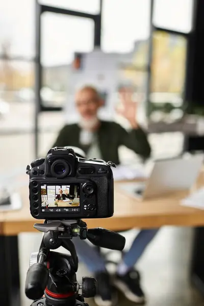Ein Mann gestikuliert, während er an seinem Schreibtisch in einem modernen Büro sitzt und an einem virtuellen Meeting teilnimmt. — Stockfoto