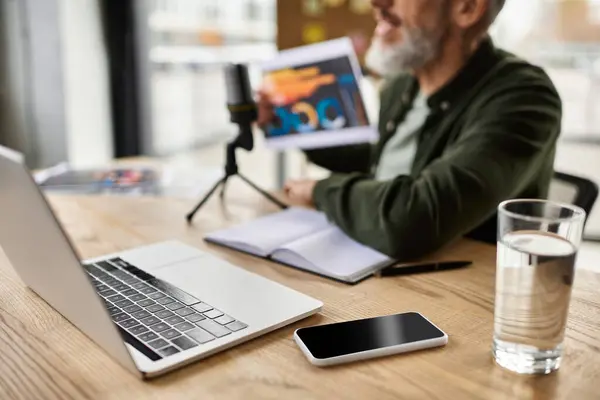 Man prepares notes while utilizing laptop and smartphone in a well lit office environment — Stock Photo