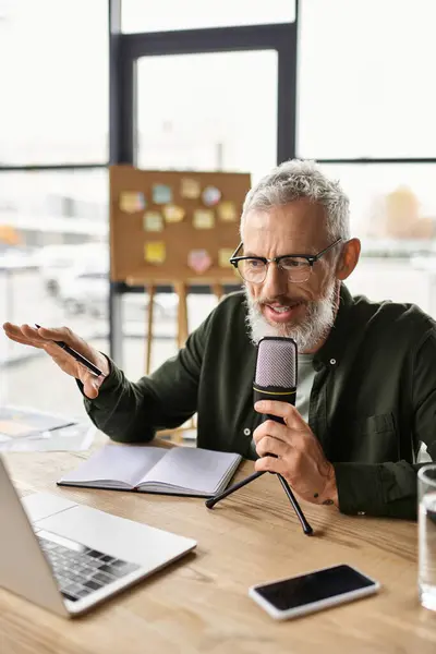 Un individuo parla appassionatamente in un microfono mentre lavora su un computer portatile in un ufficio. — Foto stock