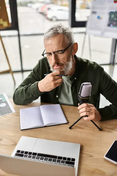 A professional reflects while preparing notes for a podcast recording in a stylish workspace. — Stock Photo