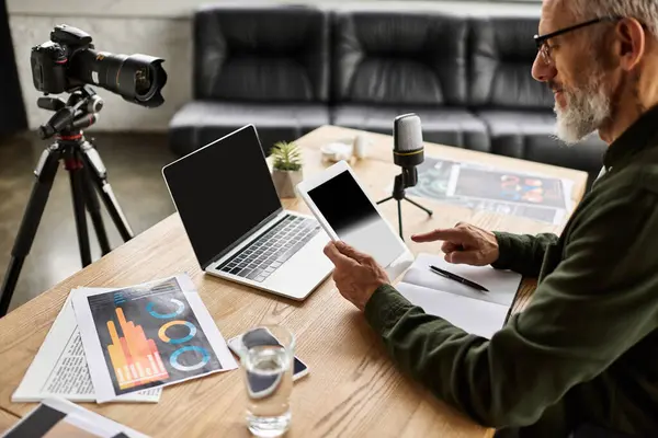 Individual engaged in digital content creation, utilizing multiple devices on a wooden workspace. — Stock Photo