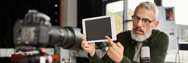 A man presents information using a tablet while sitting in a stylish office environment. — Stock Photo