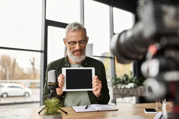 Un presentador confiado exhibe una tableta mientras prepara notas en un ambiente de oficina elegante. - foto de stock