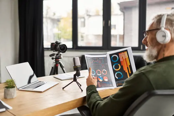 An older professional shares insights while reviewing colorful charts in a contemporary workspace. — Stock Photo