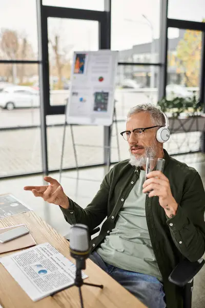 A man wearing headphones passionately discusses ideas while sipping a drink in an office. — Stock Photo