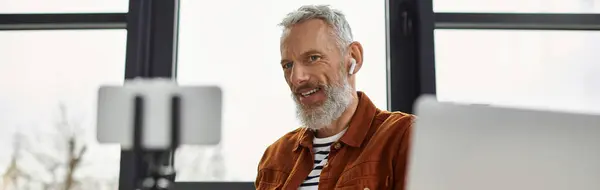 L'uomo con la barba partecipa a una discussione online, sorridendo e concentrandosi sulla sua scrivania. — Foto stock