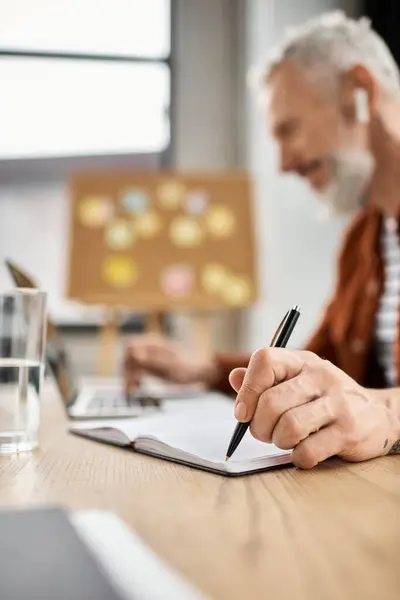 A person brainstorms on a laptop and takes notes in a notebook during work hours. — Stock Photo
