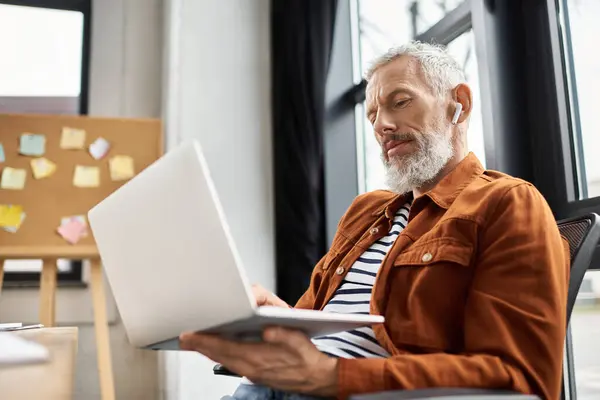 Senior man in casual wear diligently works on a laptop in an organized office. — Stock Photo