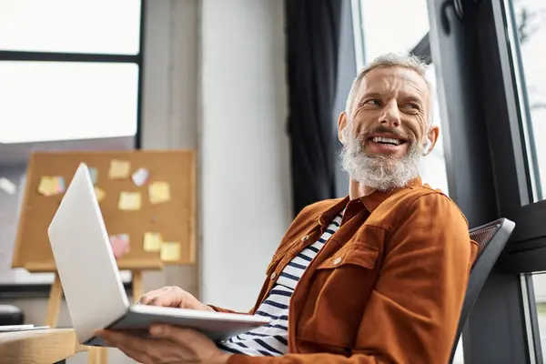 Una persona allegra lavora su un computer portatile presso una moderna scrivania dell'ufficio, godendo dello spazio. — Stock Photo