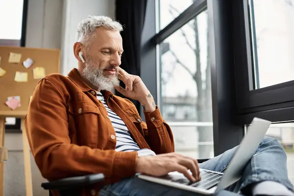 A man immersed in his tasks while seated by a large window, enjoying a calm and sunny day — Stock Photo