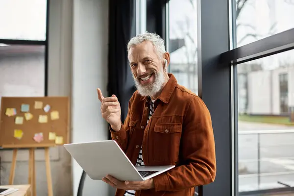 Bei einer produktiven Arbeitssitzung teilt ein lächelnder Herr mit Ohrhörern Ideen beim Tippen. — Stockfoto