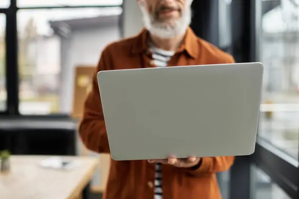 L'uomo con la barba si trova in uno spazio di lavoro contemporaneo mentre lavora al suo laptop con attenzione — Foto stock