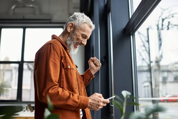 Office worker checks device while feeling joy and excitement in a bright workplace setting. — Stock Photo