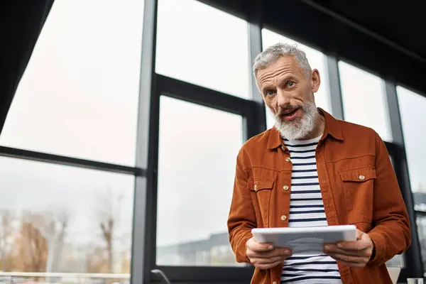 A man with a beard discusses an important topic while holding a tablet in a modern workspace. — Stock Photo