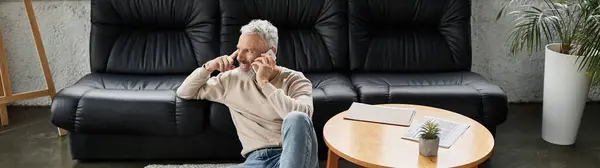 Un uomo è comodamente seduto in un ufficio elegante, impegnato in una conversazione telefonica mentre rilassato. — Foto stock