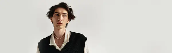 A handsome young man poses confidently in a trendy outfit at a sleek studio during a fashion shoot, banner — Stock Photo