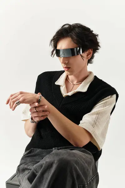 Stylish young man in a chic outfit poses confidently against a bright studio backdrop. — Stock Photo