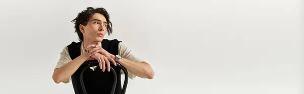 A handsome young man showcases a trendy outfit while thoughtfully leaning on a chair, banner — Stock Photo