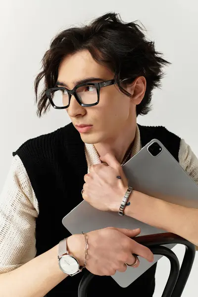 Handsome young man showcases his fashionable outfit while holding a tablet in a studio space. — Stock Photo