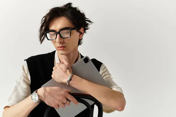 Young man with trendy outfit embraces laptop while showcasing a fashionable look in the studio. — Stock Photo