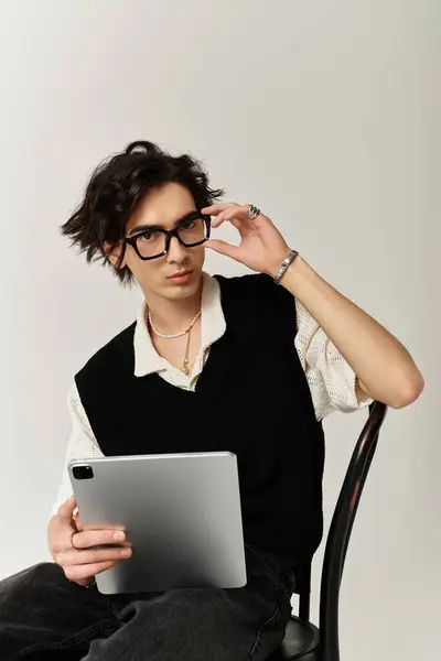 Stylish young man with glasses interacts with a tablet, exuding confidence in a creative studio. — Stock Photo