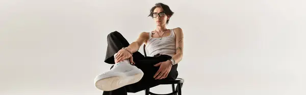 Stylish young man sits confidently in a studio, displaying casual fashion in a sleek outfit, banner — Stock Photo