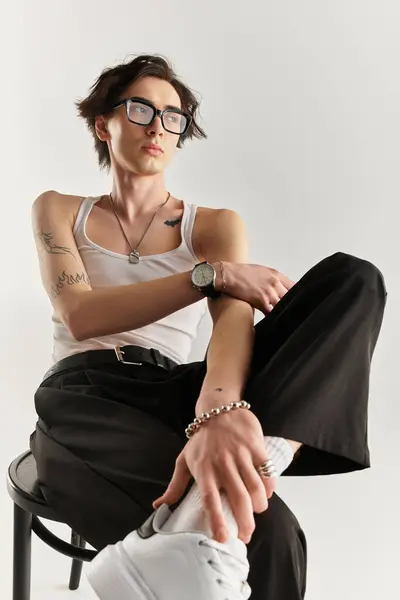 Um jovem magro posa confiantemente em um top branco, expressando estilo moderno e elegância. — Fotografia de Stock