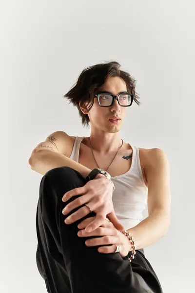 Young man poses confidently in a studio, wearing a trendy white tank top with urban flair. — Stock Photo